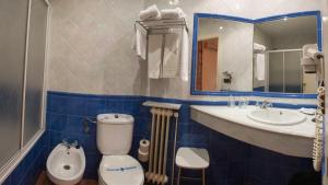 a blue and white bathroom with a toilet and a sink at Hotel Alfonso IX in Cáceres