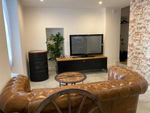 - un salon avec un canapé en cuir et une télévision dans l'établissement Cosy 2 Pièces Vue Mer Aux Parfums de Grasse, à Grasse