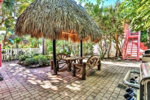 a picnic table and bench under a straw umbrella at Sunrise Garden Resort in Anna Maria