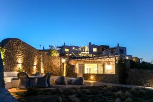 a house with a stone wall at night at Villa Anemoni by Mykonian Kazarte in Kalafatis