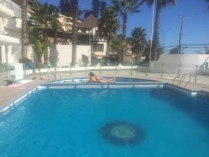 una mujer está tumbada en una piscina en Departamento Playa Paraiso, en Concón