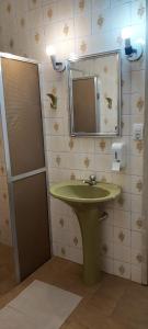 a bathroom with a green sink and a mirror at Pousada da Cléo in São Carlos