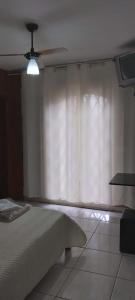 - une chambre avec un lit et un rideau blanc dans l'établissement Pousada da Cléo, à São Carlos