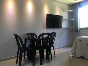 a dining room with four chairs and a tv on a wall at Apartamento na Praia - Ilhéus in Ilhéus