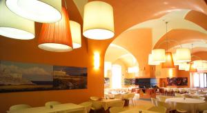 a restaurant with white tables and chairs and lights at Il Tabacchificio Hotel in Gagliano del Capo