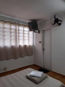 a bedroom with a bed and a fan and a window at Pousada da Cléo in São Carlos