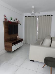 ein Wohnzimmer mit einem Sofa und einem TV in der Unterkunft Apartamento para família moderno e prático próximo a belas praias in Cabo Frio