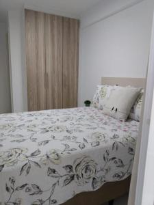 1 Schlafzimmer mit einem Bett mit Blumendecke in der Unterkunft Apartamento para família moderno e prático próximo a belas praias in Cabo Frio