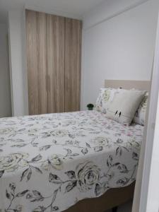 ein Schlafzimmer mit einem Bett mit geblümter Bettdecke in der Unterkunft Apartamento para família moderno e prático próximo a belas praias in Cabo Frio