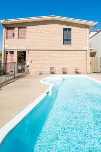 a swimming pool in front of a house at Sarina Motor Inn in Sarina