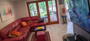 a living room with a red couch and a tv at Januce - delightful river front house in Urunga in Urunga