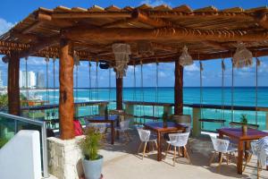 um pátio com mesas e cadeiras e o oceano em Ocean View Condo em Cancún