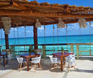 um restaurante na praia com mesas e cadeiras em Ocean View Condo em Cancún