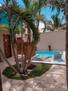 una piscina con dos palmeras en un patio en Pousada Charme Francês, en Praia do Frances