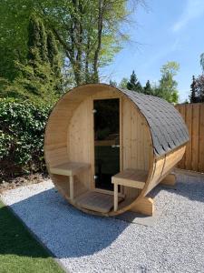 uma pequena casa de cão de madeira com dois bancos em Liv Residence Holiday Home with Sauna & Fireplace em Ermelo