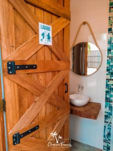 baño con puerta de madera con lavabo y espejo en Pousada Charme Francês, en Praia do Frances
