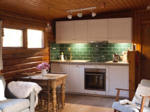 a kitchen with white cabinets and a table with a fireplace at Hillside Log cabin, Ardoch Lodge, Strathyre in Strathyre