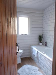 a bathroom with a tub and a toilet and a window at Hillside Log cabin, Ardoch Lodge, Strathyre in Strathyre