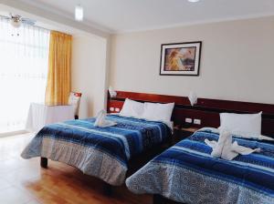 een hotelkamer met 2 bedden en een raam bij HOSTAL REAL CERRILLOS in Moquegua