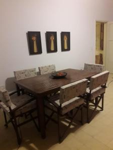 uma mesa de jantar em madeira com cadeiras e pinturas na parede em Rivahome em Córdoba