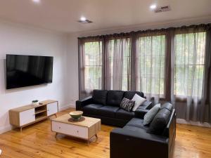 a living room with a black couch and a tv at Adelaide Brownhill Creek Tourist Park in Adelaide