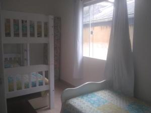 a white bedroom with a bed and a window at Casa Arraial do Cabo in Arraial do Cabo