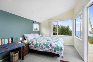 een slaapkamer met een bed en een groot raam bij Ridge Top Views - Paekakariki Holiday Home in Paekakariki
