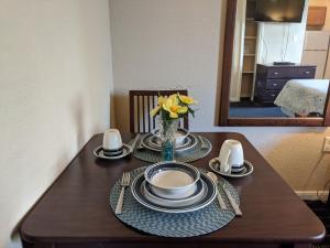 stół z talerzami i wazonem kwiatów na nim w obiekcie Athens Hotel & Suites w mieście Houston