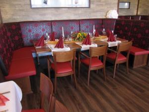 a dining room with a long table with red chairs at Hotel Krone in Haigerloch