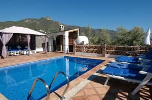 a swimming pool with blue chairs next to a house at Cortijo Mirador Casitas Select in Frigiliana