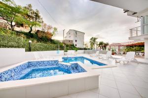 a swimming pool with white furniture and a swimming poolvisor at Vila Nikezić in Sutomore