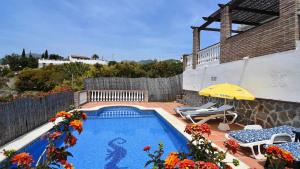 een zwembad met 2 stoelen en een parasol bij Villa La Lomilla in Nerja