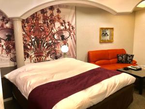 um quarto com uma cama e uma cadeira laranja em Hotel Water Gate Ichinomiya (Adult Only) em Inazawa