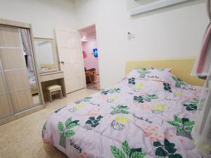 巴特沃思的住宿－Bagan Terrace House near to Sunway Carnival Mall, Seberang Jaya，一间卧室配有一张带粉红色和绿色棉被的床