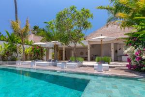a pool at a resort with chairs and umbrellas at Villa Palmdream in Karangasem