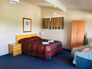 um quarto de hotel com uma cama, uma cómoda e uma cadeira em Blenheim Road Motor Lodge em Christchurch