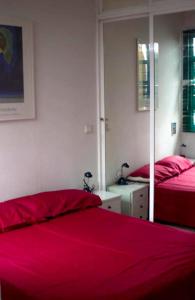 - une chambre avec 2 lits et des draps rouges dans l'établissement One bedroom apartement with city view terrace and wifi at Sevilla, à Séville