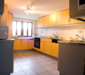 a kitchen with yellow cabinets and a tile floor at Mayen2003 Ayent Anzère in Ayent