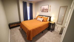 een slaapkamer met een bed met een oranje deken en een spiegel bij The Good Vibes House in Chickasha, OK! in Chickasha