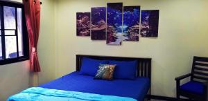 a bedroom with a blue bed with four paintings on the wall at Tonmai Aquablue in Ko Lanta