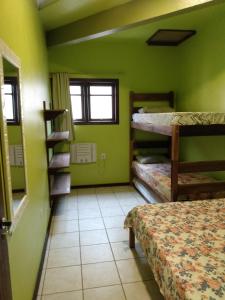 um quarto com paredes verdes e beliches em Condominio Aldeia da Praia em Garopaba