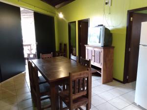 uma sala de jantar com uma mesa de madeira e uma televisão em Condominio Aldeia da Praia em Garopaba