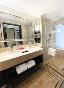 uma casa de banho com um lavatório, um espelho e um chuveiro em Lv Shou Hotel em Xangai