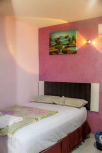 クランにあるHotel Sunsuryaのピンクの壁のベッドルーム1室