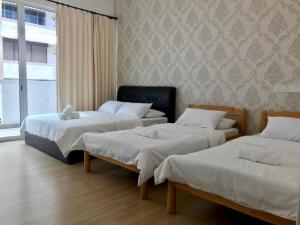 a room with three beds and a window at Island Hostel in Bayan Lepas