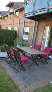 a picnic table with pink chairs in front of a building at GODS06002-FeWo-bie-de-Reede in Gollendorf