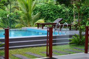 a swimming pool with two chairs and a bench next to it at Iain Lake Winds Villa in Galle +7 photos