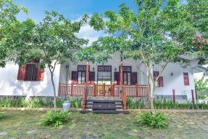 a white house with trees in front of it at Iain Lake Winds Villa in Galle