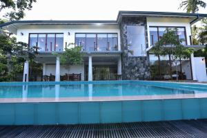 a house with a swimming pool in front of it at Iain Lake Winds Villa in Galle