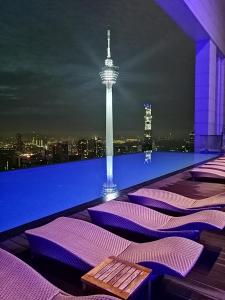 - un bar sur le toit avec des matelas violets et une aiguille pour les sièges dans l'établissement Luxe Suites at Platinum KLCC, à Kuala Lumpur